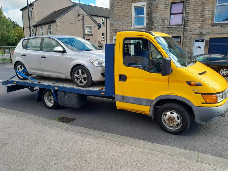 Recovery truck collecting a scrap car on a Cumbrian street